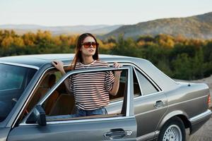 un' giovane donna autista sembra su di il auto a il autunno paesaggio e sorrisi in modo soddisfacente foto