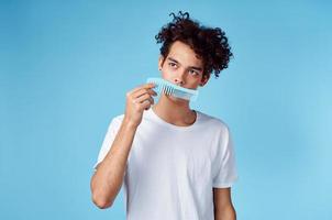 carino uomo con Riccio capelli Tenere pettine nel mano e blu sfondo ritagliata Visualizza foto