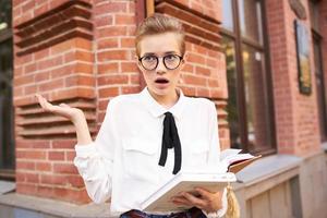 corto dai capelli donna con un' libro nel il suo mani all'aperto lettura stile di vita foto