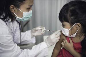 asiatico medico iniezione vaccino per proteggere virus covid-19 per un' ragazza indossare medico maschera, persone siamo ragazze siamo vaccinati contro influenza ogni anno. foto