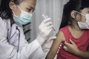 asiatico medico iniezione vaccino per proteggere virus covid-19 per un' ragazza indossare medico maschera, persone siamo ragazze siamo vaccinati contro influenza ogni anno. foto