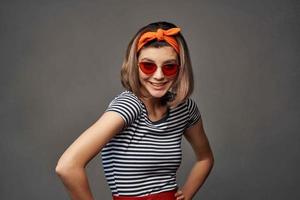 donna nel occhiali da sole con un arancia bendare su sua testa nel un' a strisce maglietta moda foto