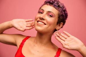 moda ritratto di un' donna con un' corto taglio di capelli di viola colore e un' Sorridi con denti nel un' rosso superiore su un' rosa sfondo felicità foto