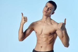 carino atleta mostrando pollice su blu sfondo nudo torso muscoli bicipite tricipiti modello foto