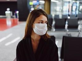 donna nel medico maschera Guarda per il lato aeroporto avvicinamento foto
