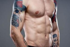 uomo con tatuaggi su il suo braccia nudo torso pompaggio su addominali allenarsi foto