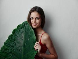 donna con verde foglia nel rosso costume da bagno attraente Guarda isolato sfondo foto