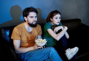 emotivo donna e uomo su il divano con Popcorn Guardando tv foto