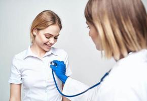 medico con un' stetoscopio e un' contento paziente su un' leggero sfondo foto