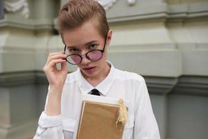 corto dai capelli donna con un' libro nel il suo mani all'aperto lettura stile di vita foto