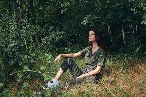 donna si siede su il erba nel il foresta e tuta scarpe da ginnastica foto
