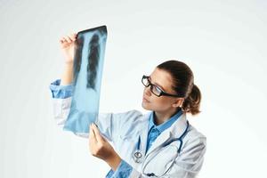 un' infermiera nel un' bianca cappotto guardare a un raggi X professionale visita medica foto