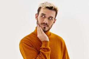 bello uomo nel maglione moda mano vicino viso studio leggero sfondo foto