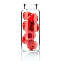 cura della pelle fatta in casa con lamponi in una bottiglia di vetro isolato su uno sfondo bianco foto