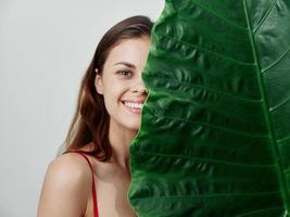 sorridente donna nascondiglio dietro a verde foglia avvicinamento esotico foto