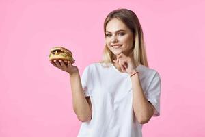 carino bionda nel bianca maglietta Hamburger delizioso cibo ristorante foto