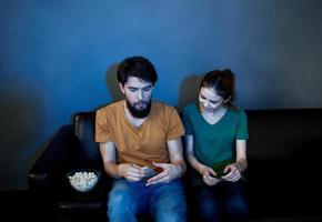 uomo e donna su pelle divano con Popcorn Guardando tv nel il sera foto