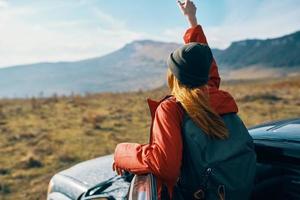 donna vicino macchine Esprimere a gesti con sua mani su natura nel il montagne autunno zaino viaggio turismo foto