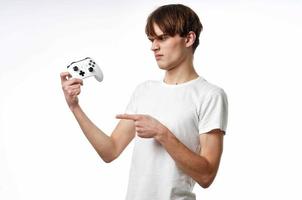 giovane tipo nel un' bianca maglietta telecomando da gioco nel il mani di il gioco emozioni leggero sfondo foto