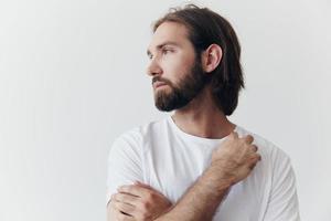 ritratto di un' uomo con un' nero di spessore barba e lungo capelli nel un' bianca maglietta su un' bianca isolato sfondo emozione di tristezza e brama foto