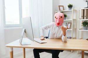 divertente pazzo donna d'affari lavoratore libero professionista nel rosa pesce maschera opera su computer in linea meditando o fabbricazione decisione scioccato di operativo i problemi aumentare mano su nel leggero moderno ufficio. copia spazio foto