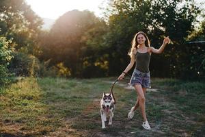 un' donna corre con un' cane nel il foresta durante un sera camminare nel il foresta a tramonto nel autunno. stile di vita gli sport formazione con il tuo Amati cane foto