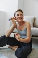 libero professionista donna con il computer portatile e Telefono lavori a partire dal casa seduta su il pavimento nel sua casa Abiti con un' corto taglio di capelli, gratuito copia spazio foto