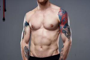 uomo con tatuaggi su il suo braccia nudo torso pompaggio su addominali allenarsi foto