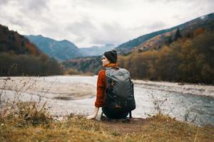 donna escursionista su il banche di il fiume nel autunno e montagne nel il distanza nuvole tempo metereologico natura foto