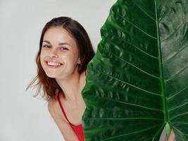 sorridente donna nel rosso costume da bagno palma foglia fascino leggero sfondo foto