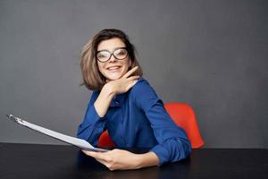 attività commerciale donna nel blu camicia si siede a il tavolo cartella nel mani documenti foto