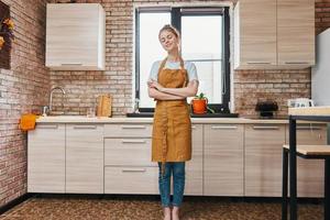 bellissimo donna nel un' Marrone grembiule cucina interno casa vita foto