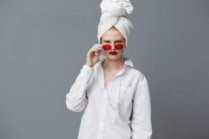 donna con un' asciugamano su il suo testa nel un' bianca camicia isolato sfondo foto