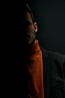 silhouette di un' uomo nel un' maglione e giacca su un' nero sfondo caduta ombra foto