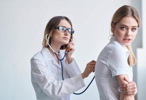 professionale medico donna con stetoscopio e femmina paziente lato Visualizza foto