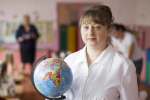 ritratto di un' insegnante con un' globo.anziani donna insegnante. foto