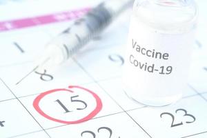 primo piano del vaccino contro il coronavirus e la siringa su un calendario con un cerchio rosso