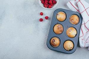 al forno lampone muffin su un' raffreddamento cremagliera su blu calcestruzzo tavolo sfondo. superiore Visualizza, copia spazio. foto