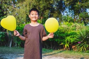 ragazzo felice che tiene palloncini gialli foto