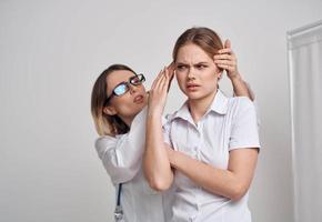 professionale medico donna nel bicchieri tocchi il testa di il paziente su un' leggero sfondo foto