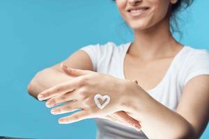 donna con crema su sua mani idratante pelle cura blu sfondo foto