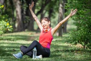 sport donna respirazione profondamente fresco aria con braccia sollevato all'aperto nel urbano parco con sfocato sfondo foto