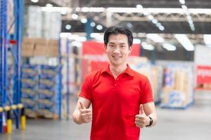 allegro uomo sorridente con dando pollici su, magazzino lavoratore Lavorando nel fabbrica magazzino foto