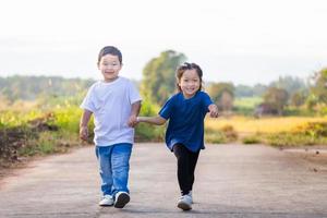 contento giocoso bambini in esecuzione all'aperto nel primavera parco. asiatico bambini giocando nel giardino, ragazzo e ragazza foto