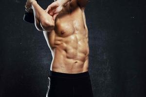 uomo con pompato su muscolare corpo allenarsi esercizio Palestra buio sfondo foto