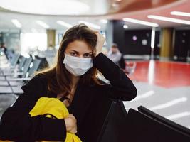 donna nel medico maschera detiene mano su testa giallo zaino aeroporto passeggeri foto