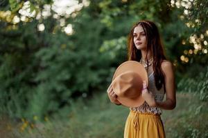 un' donna vestito come un' hippie con trecce su sua testa viaggi all'aperto a un' campeggio nel il autunno e gode vita foto