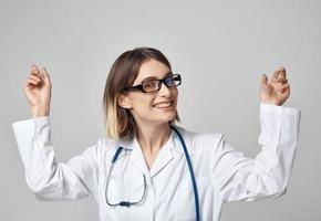 femmina infermiera nel un' medico toga Esprimere a gesti con sua mani su un' leggero sfondo foto