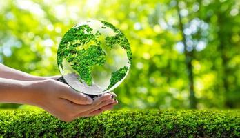 concetto salva il mondo salva ambiente il mondo è nell'erba dello sfondo verde bokeh foto