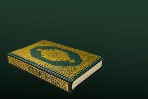 il santo al Corano con scritto Arabo calligrafia senso di al Corano e rosario perline o tasbih su buio verde nero sfondo con copia spazio. foto
